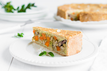 Meat-pie with carrots, red beans and peas on white plate
