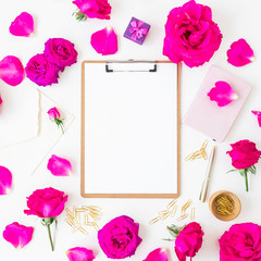 Workspace with clipboard, notebook, roses flowers and accessories on white background. Flat lay, top view.