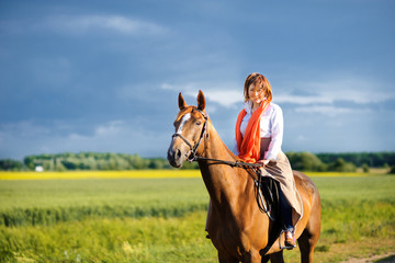 woman rides a horse in the beautiful beautiful field on a sunset