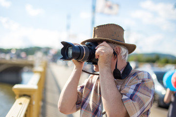 Obraz premium Senior tourist man in hat photographing during trip
