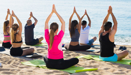 People in lotus positions looking at sea