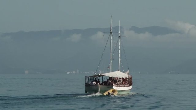 Tour boat with tourists sailing away from Ilhabela, Brazil