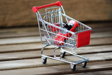 New car acquisition concept with red toy cad in shopping cart