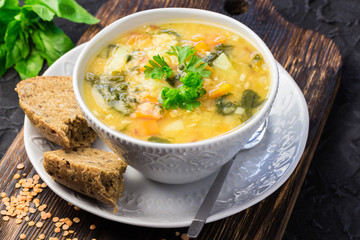 Golden lentil spinach soup on wooden dark background.