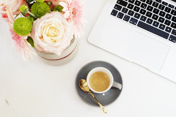 Feminine workplace concept. Freelance fashion comfortable femininity workspace in flat lay style with laptop, coffee, flowers on white marble background. Top view, bright, pink and gold