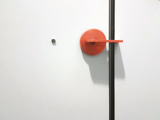 red door knob on white door with a screw