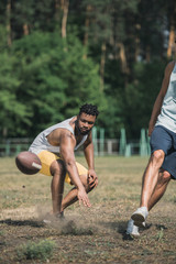 group of young multicultural men playing football on court