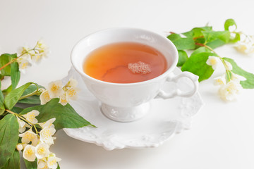 Cup of tea with jasmine flowers on a white table