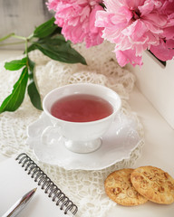 Red berry or fruit tea in teacup with peony