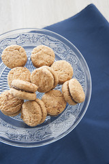Lady's Kisses (pastry pastries with almond and chocolate) on glass cake stands worked. Blue prussia tablecloth as a background.