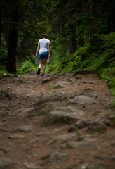 Obraz premium Hiker in mountain forest carries bottled water