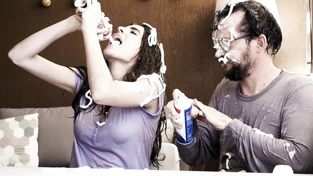 Funny prank man putting sprinkling cream on head and hair of girlfriend eating it 160fps slow motion closeup