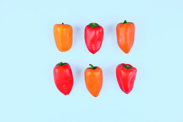 Red, orange, yellow paprika on blue background.