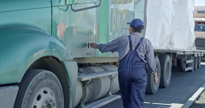 Tilt up slow motion of African delivery woman getting into driver cabin of large truck