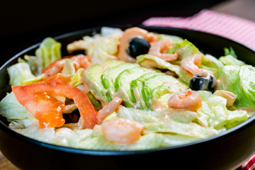 Delicious fresh salad with tomatoes, lettuce, eggplant, zucchini, cheese, parma ham and olive oil.