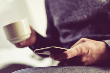 young man with a coffee using a smartphone