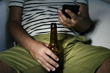 man drinking a beer and using his phone