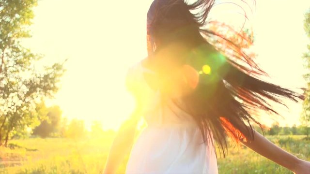 Beauty sexy brunette girl in short white dress walking on field with wildflowers, enjoying nature outdoors. Slow motion 240 fps. 4K UHD video 3840x2160