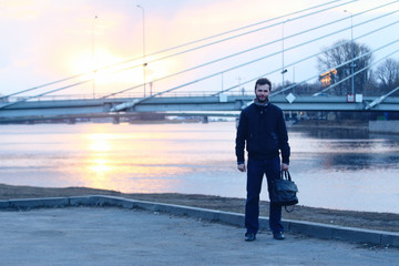 Obraz premium Young man to the utmost on the embankment and bridge on the backstage. 