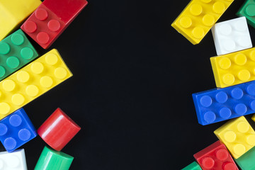 Plastic toy bricks on black background. Copy space