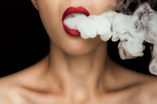 cropped view of naked woman with red lips blowing smoke, isolated on black