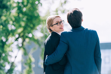 Fototapeta premium back view of middle aged business people embracing while standing together on street
