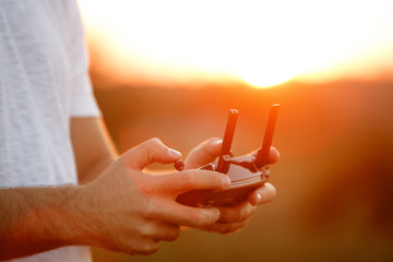 Man holds a drone remote controller in his hands. Close-up of quadrocopter RC during flight. Pilot...