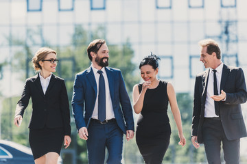 professional team of middle aged multiethnic businesspeople walking together and talking in city