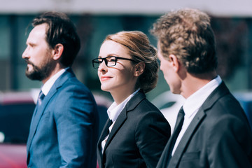 beautiful blonde businesswoman standing between confident middle aged businessmen