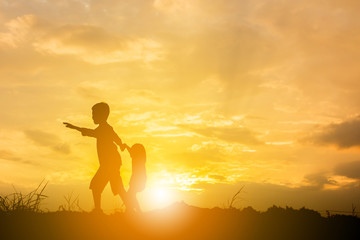 Silhouette of Boy and girl playing at sunset background, Happy children concept.