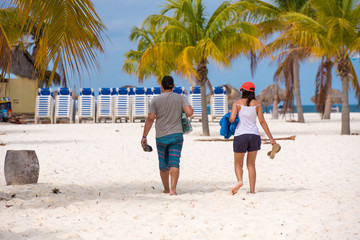 A man and a woman go to Playa Sirena beach, Cayo Largo, Cuba. Back view.