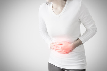 Woman stomachache on gray wall background.