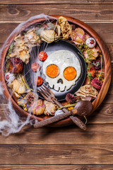 Fried eggs in the shape of a skull and fresh tomatoes. Breakfast in Halloween decorations.