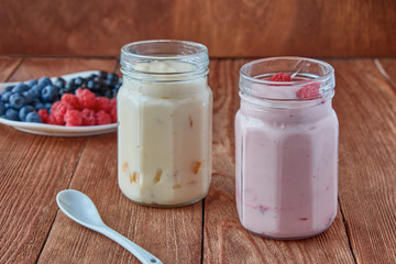 Delicious, healthy yogurt with fresh berries. Black currant, raspberry, blueberries and yogurt on a wooden background.