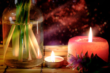 Obraz na płótnie Canvas Pink flower of Pink Siam Tulip or Curcuma sessilis flower in vase and burning candle light with light Pink bokeh background. Concept of peace, meditation, hope and relaxation