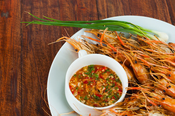 Heap of barbecue grilled shrimps on white plate with spicy chili sauce