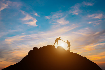  Silhouette of couple teamwork  hiker helping each other on top of mountain
