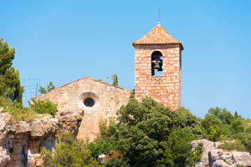 Fototapeta na wymiar View of the Romanesque church of Santa Maria de Siurana, in Siurana de Prades, Tarragona, Catalunya, Spain. Copy space for text. Isolated on blue background.
