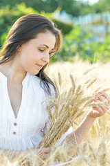 Beautiful young sexy woman holding wheat ears at summer sunny day. Portrait of pretty girl outdoor