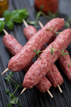 Close-up of raw cevapcici or balkan skinless beef sausages on skewers, selective focus