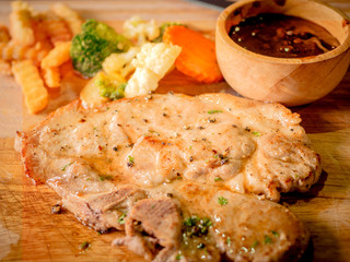 Delicious steaks with seasonings and herbs on wooden dish.