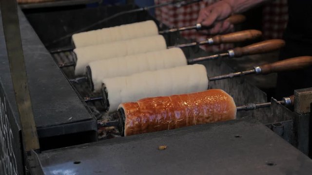 Traditional Czech and Hungarian sweet bakery trdelnik cooked on the street of Budapest, slowmotion