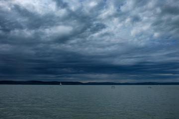rain clouds over Balaton lake sailboat on the water - cold, cloudy, stormy weather in summer season