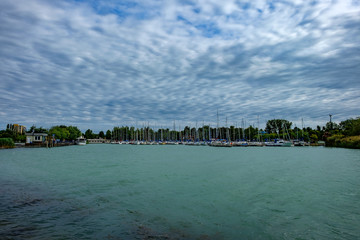 sailing harbor at Balaton lake summer holiday starts - cloudy sky, green water, sailing boats in background