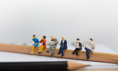 Miniature people sitting on pencil using as background education or business concept