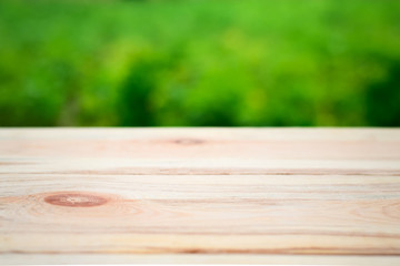 Wooden table on a background of bright green trees in the defocus