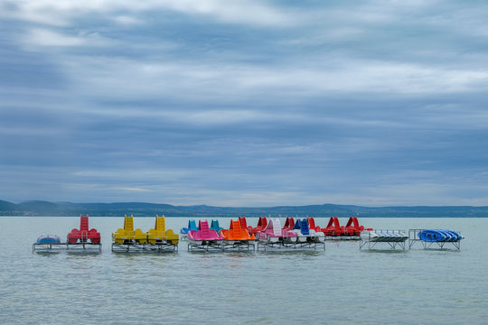 colorful paddle boats at Balaton lake waiting for summer season - over water, cloudy and windy weather, ready for holiday