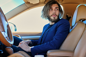 Casual bearded male with long hair in a car.