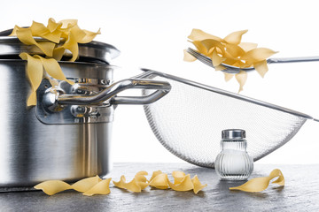 Bandnudeln, Pasta, Kochen, Topf, Nudeln, Salzstreuer und Nudelsieb, vor hellem Hintergrund auf...