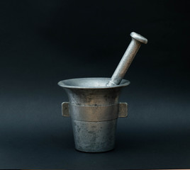 Old aluminium mortar and pestle on black background